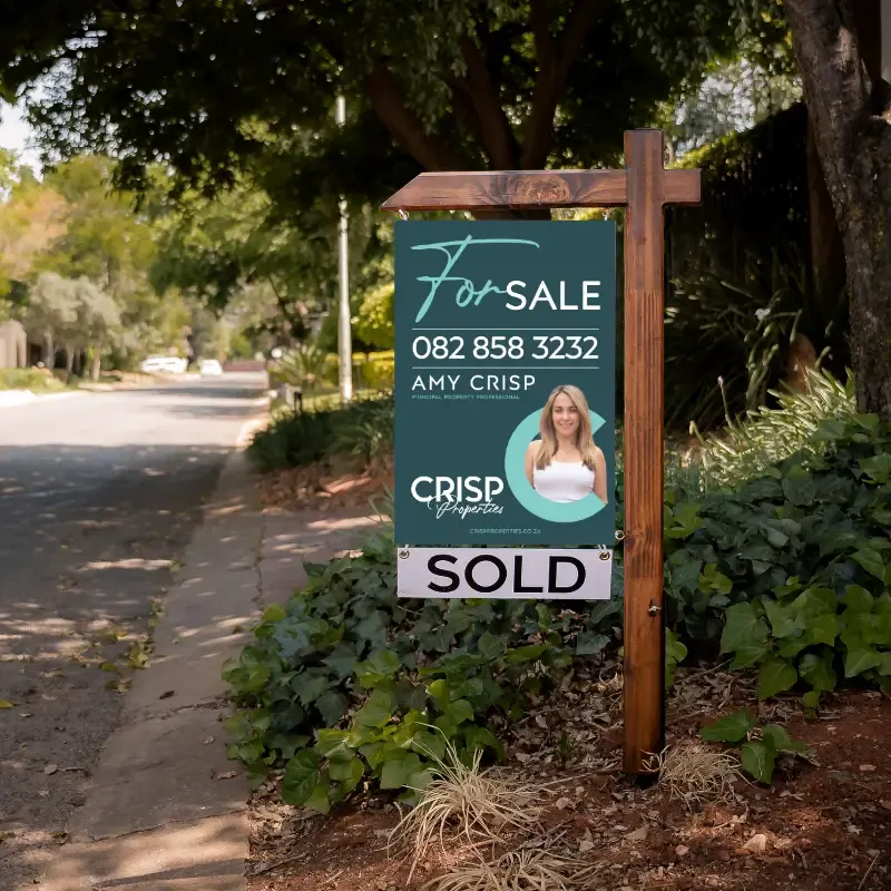 A Crisp Properties for sale board with a SOLD sign, outside a leafy home